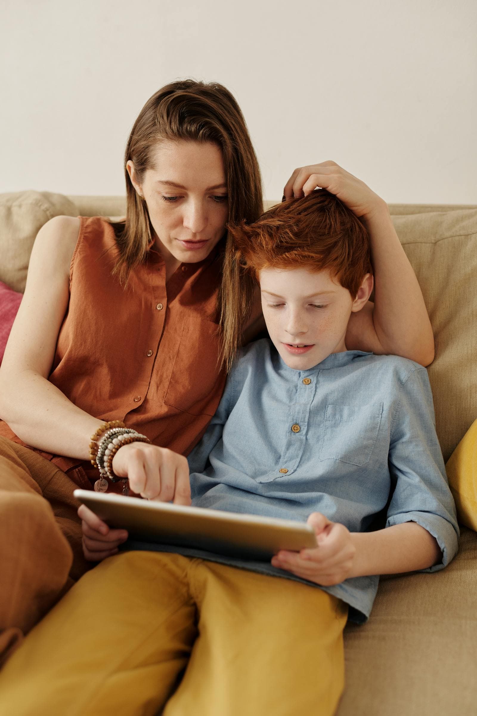 A parent and child sitting on the couch using a tablet together